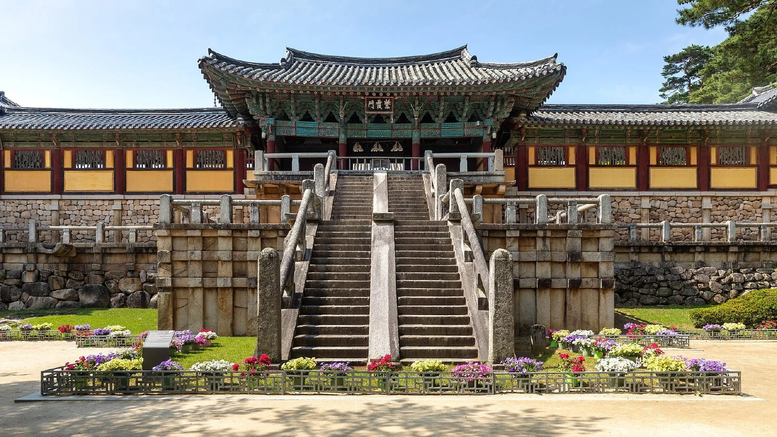 맑은 하늘 아래 경주 불국사 입구의 돌계단과 누각, 앞쪽 화단