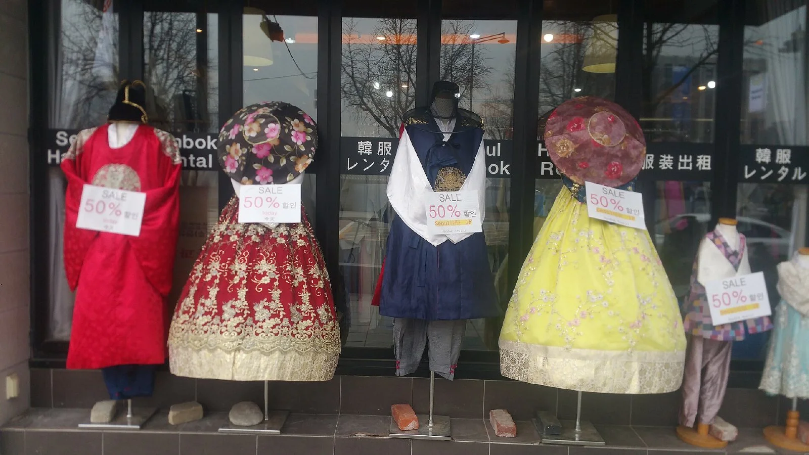 경복궁과 광화문광장 옆 거리에 한복 대여점 간판과 대여용 한복이 늘어서 있는 모습